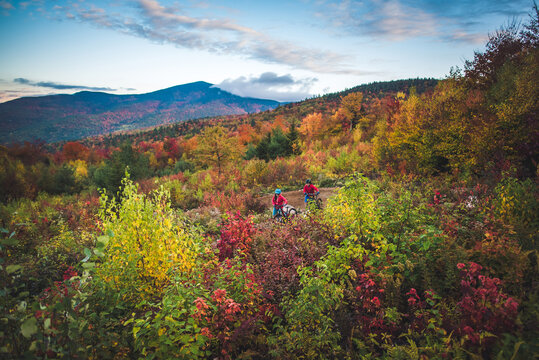 Male and female hiking with mountain bikes during fall foliage season - Powered by Adobe