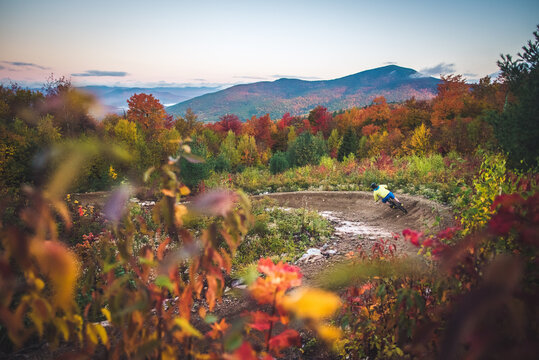 Male mountain-biking down berms during fall foliage season