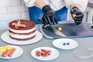 Pastry chef slices kumquat fruit to decorate the bare cake