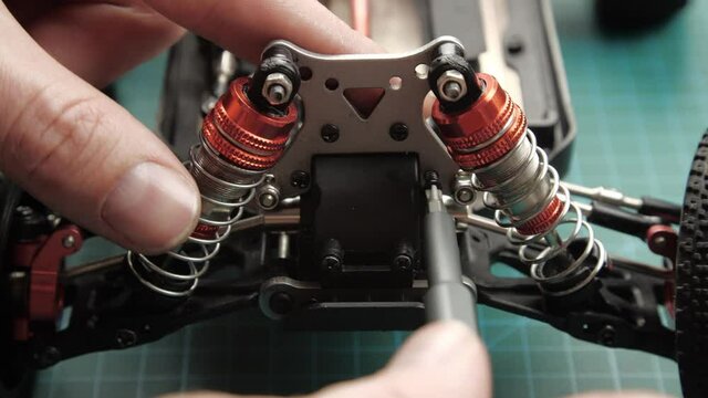 Close-up radio control model buggy car. The hands of the master assemble the front suspension