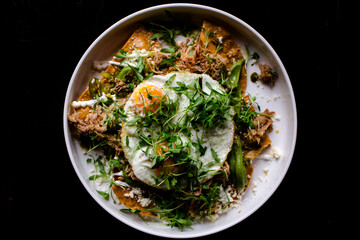 Above-view of Mexican huevos rancheros on dark background