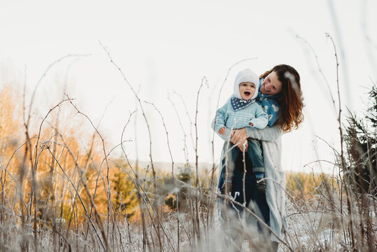 Mother holding child in arms on a sunny day in frosted field winter