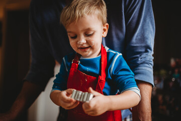 Adorable boy baking Christmas cookies with face full of flour
