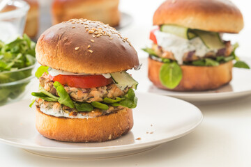 Two portions of fresh, homemade salmon burgers on white plate