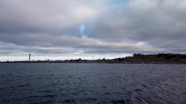 Panning shot over the oresund, &ouml;resund, body of water in Malm&ouml;, Sweden. The turning torso in the horizon on a beautiful cloudy day. 4K