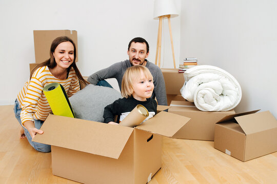 Mom plays with son pushing box with him, young family just bought a new home. Real life image