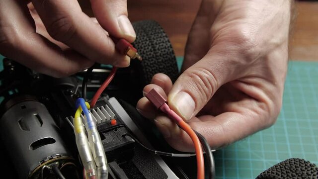 Close-up radio control model buggy car. The hands of the master connecting the battery of model