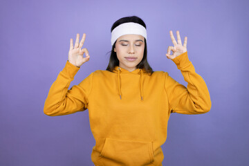 Young latin woman wearing sportswear over purple background relax and smiling with eyes closed doing meditation gesture with fingers