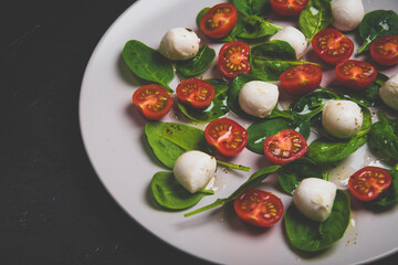 Salad with mozzarella and baby spinach on light ceramic plate. Matte toned