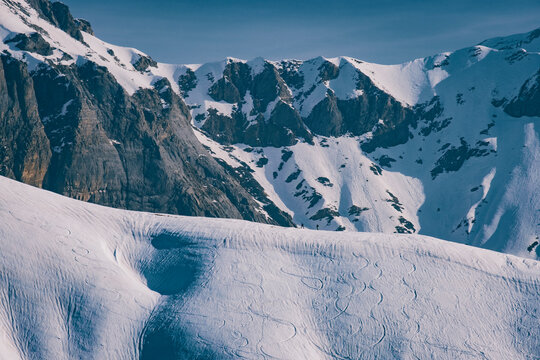 Two unrecognisable backcountry skiers against cloudy sky and mountains