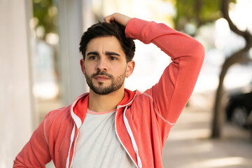 Young man looking stressed and worried outdoors.