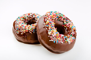 Closeup of funny chocolate donuts covered with many colorful sprinkles isolated on white background