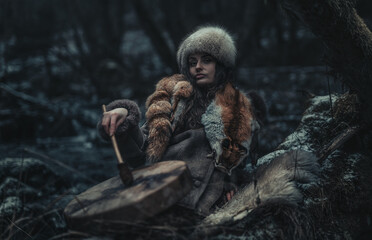 beautiful shamanic girl playing on shaman frame drum in the nature.