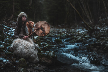 Fototapeta na wymiar beautiful shamanic girl playing on shaman frame drum in the nature.