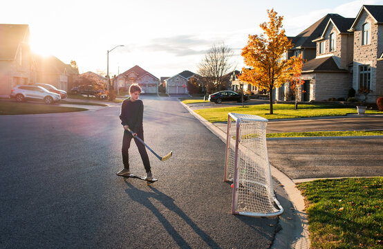 Teen boy playing street hockey on ripstick on a residential street.