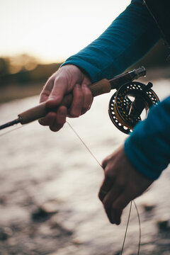 Detail of fly-fisherman stripping line while fishing in twilight