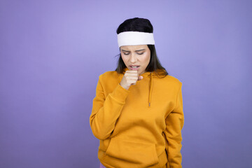 Young latin woman wearing sportswear over purple background with her hand to her mouth coughing