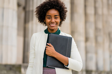 Afro businesswoman holding clipboard outdoors at the street.