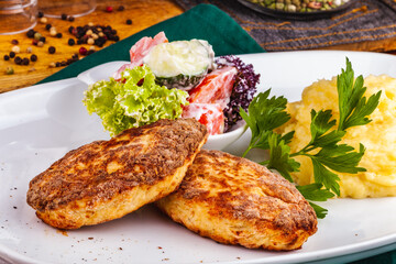 Chicken cutlets, mashed potatoes and vegetable salad on a white plate