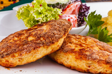 Chicken cutlets, mashed potatoes and vegetable salad on a white plate