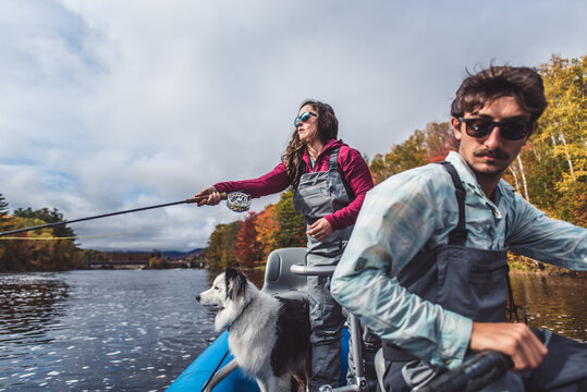 Man and woman anglers with dog in a boat during foliage season