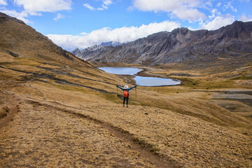 A trekker with Laguna Susucocha on the background from Tapush Punta on the Cordillera Huayhuash circuit, Ancash, Peru
