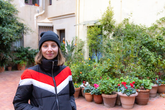 blond girl with black hat in winter, surrounded by flowers and plants