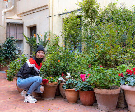 blond girl with black hat in winter, surrounded by flowers and plants