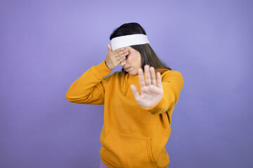 Young latin woman wearing sportswear over purple background covering eyes with hands and doing stop gesture with sad and fear expression. Embarrassed and negative concept.