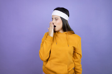 Naklejka na ściany i meble Young latin woman wearing sportswear over purple background bored yawning tired covering mouth with hand. Restless and sleepiness.