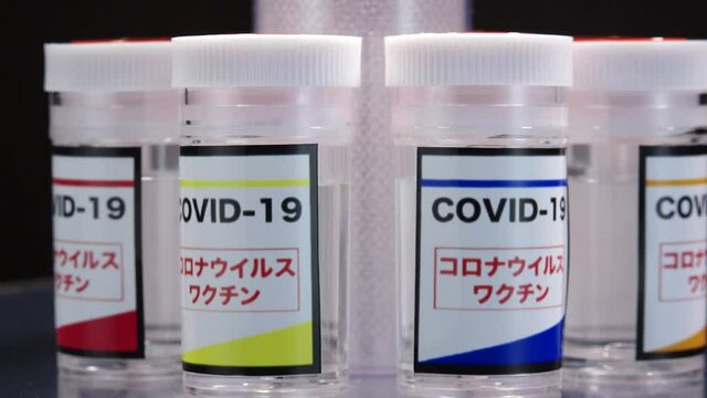 CORONAVIRUS (COVID-19) VACCINE close up shot. Colorful glass bottle of liquid remedy for injection use. Manufacture drugs for medical supplies of pharmacy industry. Label in Japanese language.