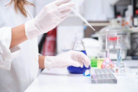 Unrecognizable young scientist using a Pasteur pipette and a rack with tubes. Laboratory research concept.