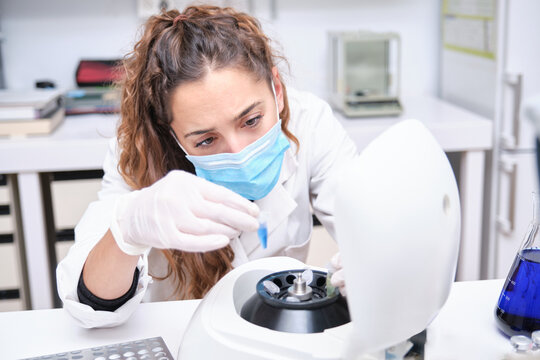 Young female scientist working in a laboratory sampling DNA in a test tube with a centrifuge. Laboratory research concept.