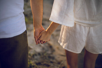 couple in love holding hands and walking on the beach at sunset