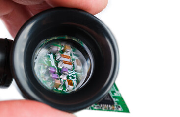 Miniature inductors, resistors and capacitors in loupe on a white background. Semiconductor...