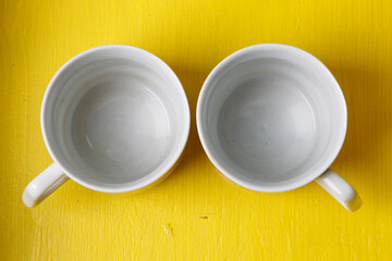 two white mugs on yellow