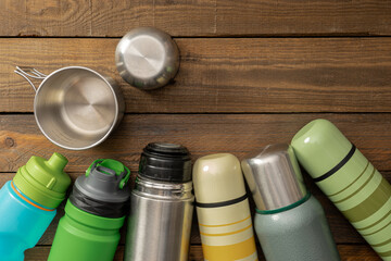 Stainless cup, vacuum flask on the wooden table background with copy space. Camping.