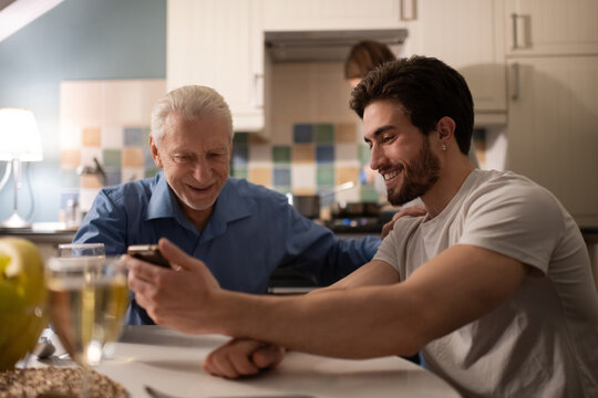 Senior father supporting son while watching photos together
