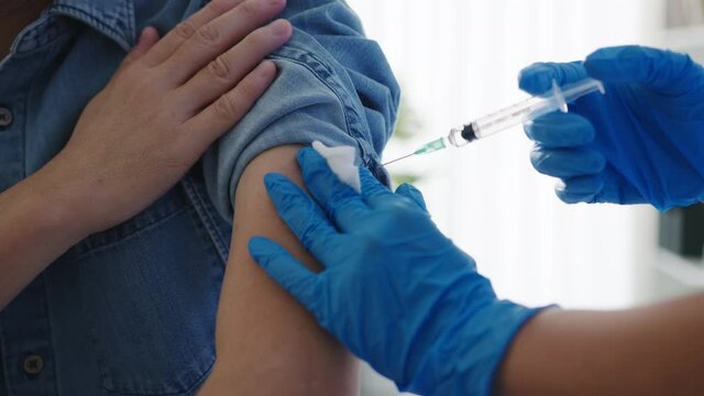 Young Asia lady nurse giving Covid-19 or flu antivirus vaccine shot to senior male patient wear face mask protection from virus disease at health clinic or hospital office. Vaccination concept.