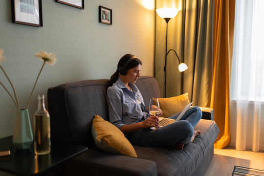 Young woman with glass of wine using laptop at home