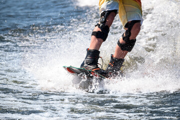 Wakeboard. Athlete's feet on the board on the wave. Special equipment for fixed knees