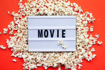 Popcorn, lightbox text Movie time on red paper background. Top view Template