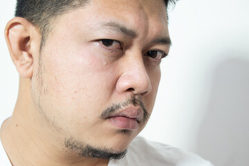 Obraz premium Portrait of unhappy and depressed man with black hair, feeling ashamed or sick, keeping eyes closed. Human face expressions and emotions concept. Isolated studio shot on gray background.