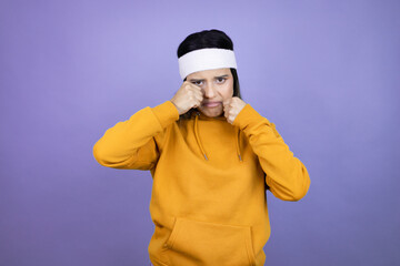 Young latin woman wearing sportswear over purple background depressed and worry for distress, crying angry and afraid. Sad expression.