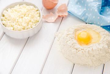 Baking cake in rustic kitchen - dough recipe ingredients eggs, flour, milk, butter, sugar on white planked wooden table from above. Background layout with free text space