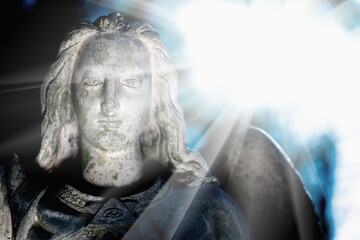 Obraz premium Beautiful guardian angel in sun rays. Bery ancient stone statue.