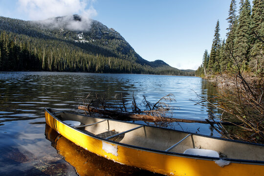 Yellow canoe floats on the shore of remote alpine lake on sunny day