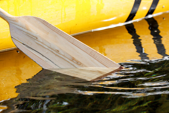 Close-up of canoe paddle dipping in tranquil remote lake