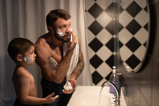 Father showing son how to smear shaving foam