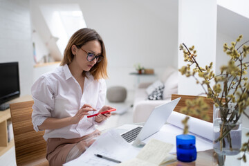 Busy woman working at home and using smartphone